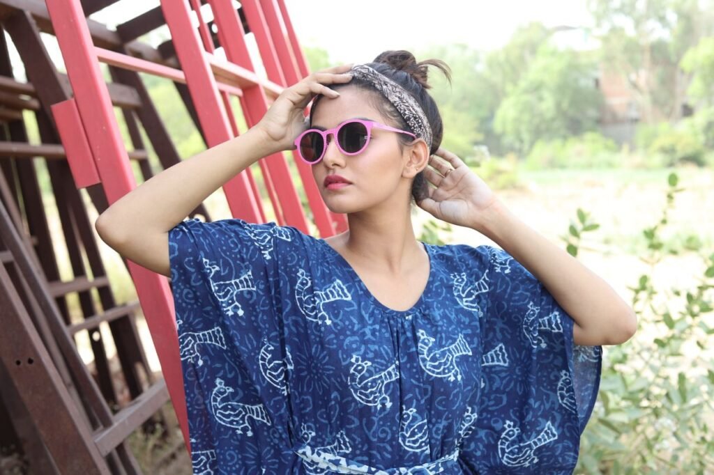 Stylish woman in blue patterned dress and sunglasses, outdoors.